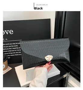 Détail de la pochette enveloppe noire avec texture ondulée brillante et boucle dorée