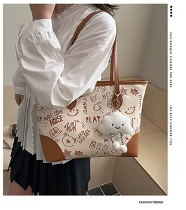 Detail of printed tote bag with graffiti art, brown leather trim and plush cloud charm