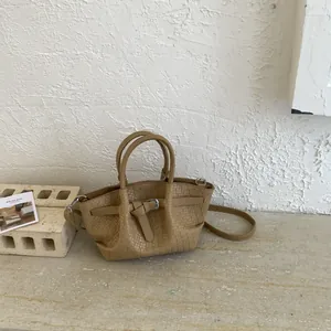 Detailed close-up of light brown woven texture and silver metal buckle on bucket bag