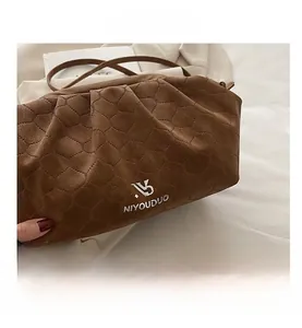 Detailed close-up of brown embossed leather texture and logo on the stylish cloud bag