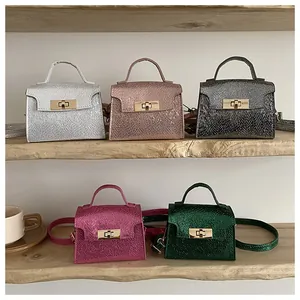 Close-up of stylish metallic textured mini bags with metal turn-lock on a wooden shelf