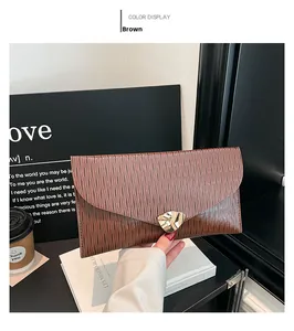 Détail de la pochette enveloppe marron avec boucle dorée et texture gaufrée à effet d'eau