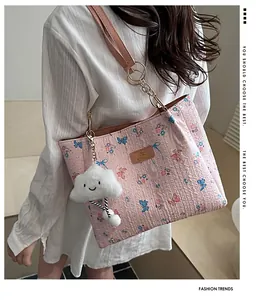 Close-up of pink tote bag with blue butterfly prints and plush cloud charm accessory