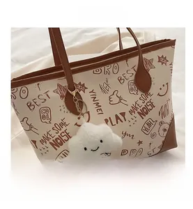 Close-up of white graffiti tote bag with brown straps and cute cloud plush keychain
