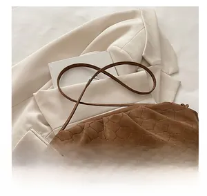 Detail showing the knotted shoulder strap and hexagonal quilted texture of the brown cloud bag