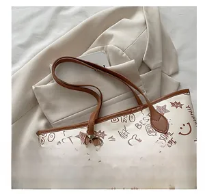 Close-up of oversized graffiti tote bag with plush cloud charm on a beige blazer