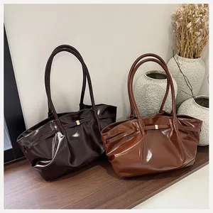 Vue détaillée des sacs cabas plissés brillants avec boucles dorées et longues bandoulières