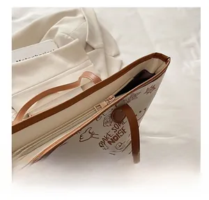 Detailed close-up of the smooth gold-tone zipper and white graffiti tote bag