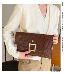 Détail d'une pochette enveloppe marron foncé avec texture plissée et boucle dorée élégante