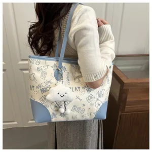 Detail of printed tote bag with blue trim and cute plush cloud charm for daily commute