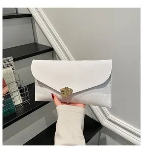 Détail d'une pochette enveloppe blanche avec texture ondulée et boucle en métal doré