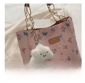 Macro view of pink floral butterfly tote bag with plush cloud charm and metal chain strap
