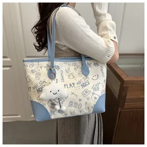 Detail of printed tote bag with graffiti pattern and plush cloud charm on shoulder
