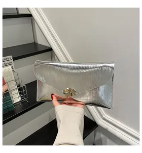 Détail de pochette enveloppe argentée avec texture ondulée et boucle métallique moderne
