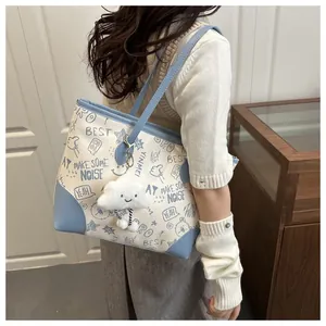 Detail view of large graffiti tote bag featuring trendy prints and a plush cloud charm