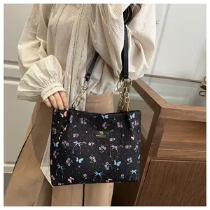 Detail of butterfly print tote bag featuring textured fabric and gold chain handle