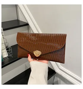 Détail d'une pochette enveloppe marron avec texture plissée et boucle en métal doré