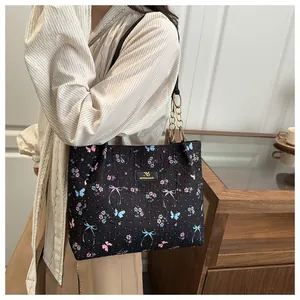 Detailed view of the textured butterfly print tote bag with gold metal chain strap