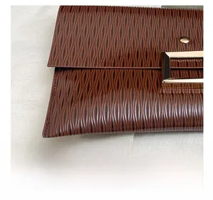 Détail macro du sac en cuir PU marron avec textures ondulées et fermoir en métal doré