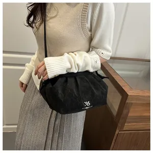 Detail of black quilted cloud bag with white logo print and slim leather shoulder strap