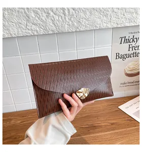 Détail macro de la pochette enveloppe marron texturée avec un fermoir en métal doré
