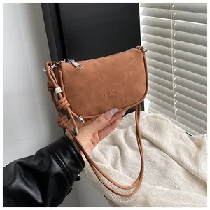 Detail der Mini-Schultertasche aus Wildleder mit M-Metallanhänger und elegantem Kordelzug
