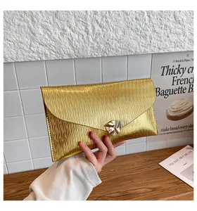 Détail de pochette enveloppe dorée élégante avec texture plissée et fermoir en métal