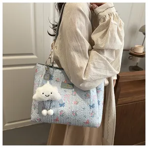 Detail of light blue butterfly tote bag with floral patterns and plush cloud keychain