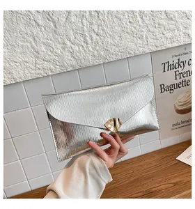 Détail de la pochette enveloppe argentée avec boucle feuille dorée et texture ondulée