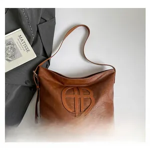 Détail du grand sac cabas en similicuir marron foncé avec logo AB et bandoulière