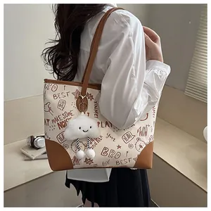 Detail of printed canvas tote bag with brown leather trim and cute cloud plush charm