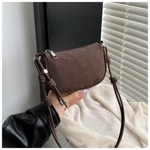 Detail der dunkelbraunen Wildleder-Halbmondtasche mit minimalistischem Knotengurt und Metall