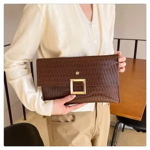 Détail d'une pochette marron foncé avec plis verticaux et grande boucle dorée