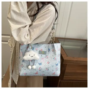 Detailed view of light blue tote bag with floral patterns and plush cloud charm