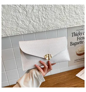 Détail de la pochette enveloppe blanche avec texture ondulée et boucle dorée