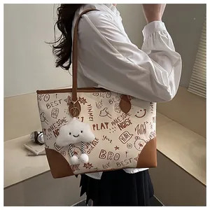 Detail of printed tote bag with brown straps and cute white cloud plush pendant accessory