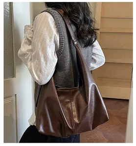 Dettaglio di una grande borsa hobo in ecopelle marrone scuro indossata da una modella