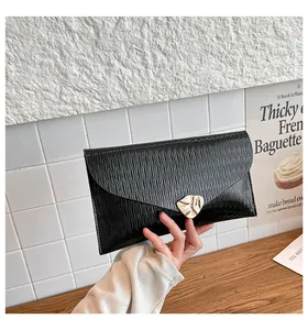 Détail d'une pochette enveloppe noire à texture ondulée et fermoir feuille dorée à la main