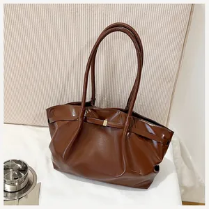 Détail d'un sac seau en cuir marron brillant avec boucle dorée et bandoulière fine