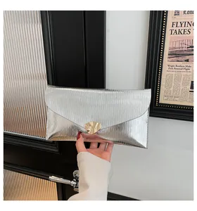 Détail de la pochette enveloppe argentée avec plis verticaux et fermoir doré chic