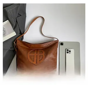 Détail du sac cabas en cuir marron montrant sa grande capacité avec une tablette