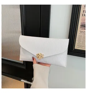Détail de la pochette enveloppe blanche avec texture ondulée et boucle dorée