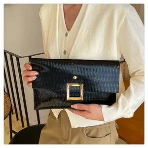 Détail de la pochette enveloppe noire avec texture plissée et boucle dorée carrée