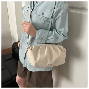 Detail view of beige quilted cloud bag with gold logo and delicate shoulder strap