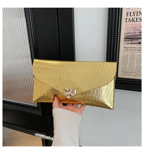 Détail d'une pochette enveloppe dorée de luxe avec texture ondulée et boucle en métal ondulé
