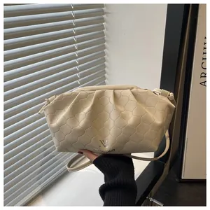 Detail view of cream pleated cloud bag with quilted texture and brand logo
