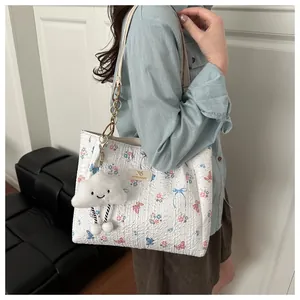 Close-up of white floral butterfly tote bag with gold logo and plush cloud charm detail