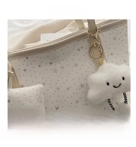Detail of white tote bag with star print and cute plush cloud pendant accessory