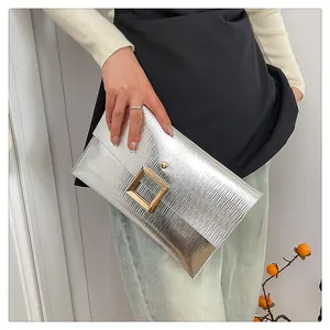 Détail de la pochette argentée à texture ondulée avec boucle carrée dorée géante