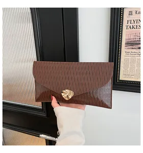 Détail d'une pochette enveloppe marron avec texture ondulée et boucle en forme de feuille dorée